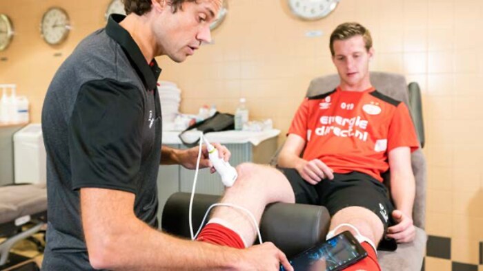 Healthcare professional using handheld ultrasound on athlete's knee